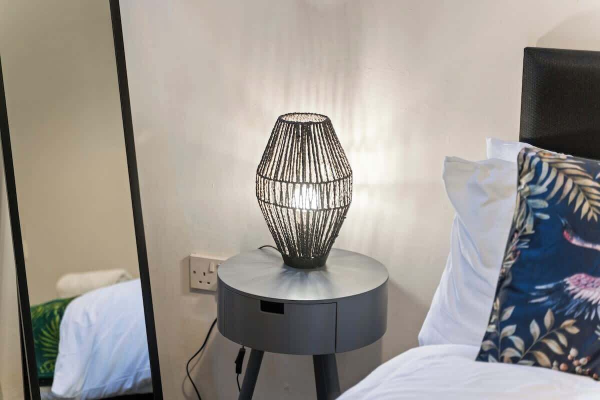 A modern lamp on a bedside table in a hotel room.