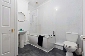 Un baño moderno con bañera, lavamanos e inodoro.