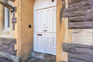 A white double door with a number plate, set in a yellow wall with stone accents. - Sienna's Apartment -2 Bed getaway in Pontypool (Pontypool)