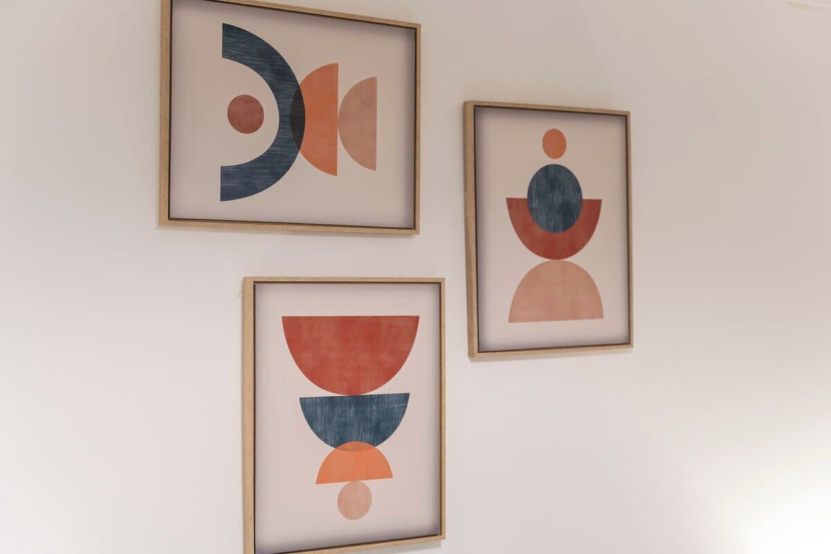Three framed abstract artworks on a plain wall.