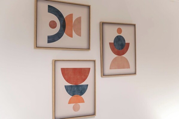 Three framed abstract artworks on a plain wall.