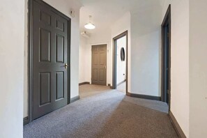 A hallway with carpeted floors, a ceiling light fixture, and two doors.