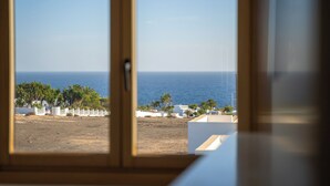 A view from a window overlooking a beach with palm trees and a clear blue sky. - BLASCO by Buenavilla | luxury and comfort in an unrivalled setting (Puerto Calero)
