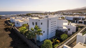 A coastal residential area with modern white buildings, some with flat roofs and others with sloped roofs, arranged in a grid pattern. - BLASCO by Buenavilla | luxury and comfort in an unrivalled setting (Puerto Calero)