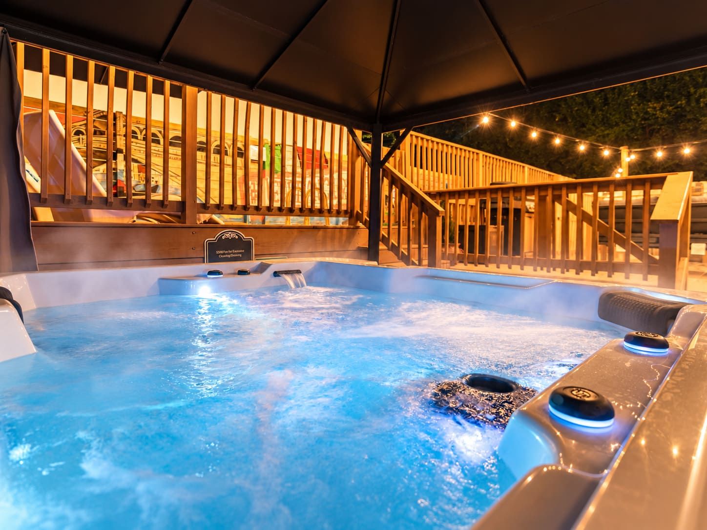 A hot tub with a wooden deck and a sign indicating a $50 fee for entry.