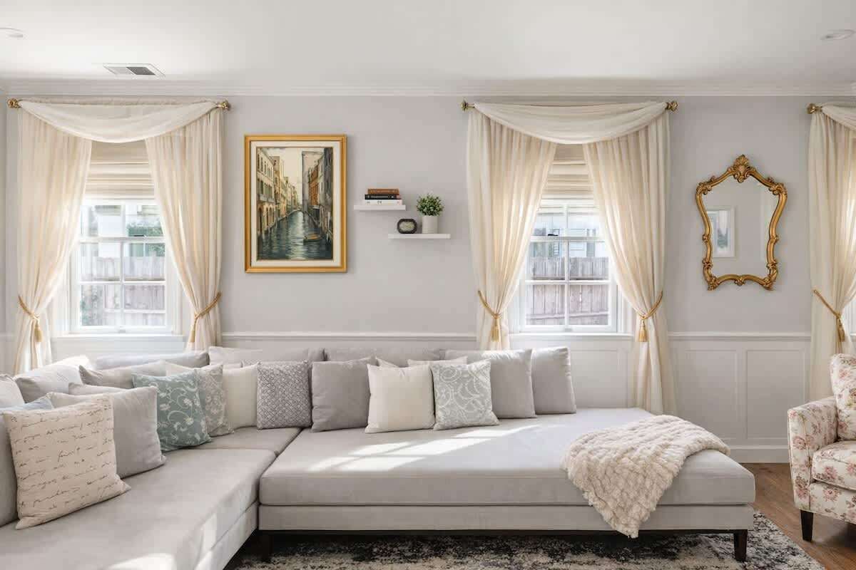 Una sala moderna con un sofá seccional, un cuadro grande enmarco y un espejo decorativo.