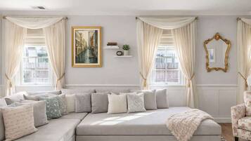 Una sala moderna con un sofá seccional, un cuadro grande enmarco y un espejo decorativo.