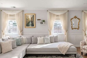 A modern living room with a sectional sofa, a large framed picture, and a decorative mirror. - Hot Tub & Sauna | Newly Renovated Outside (Charlotte)