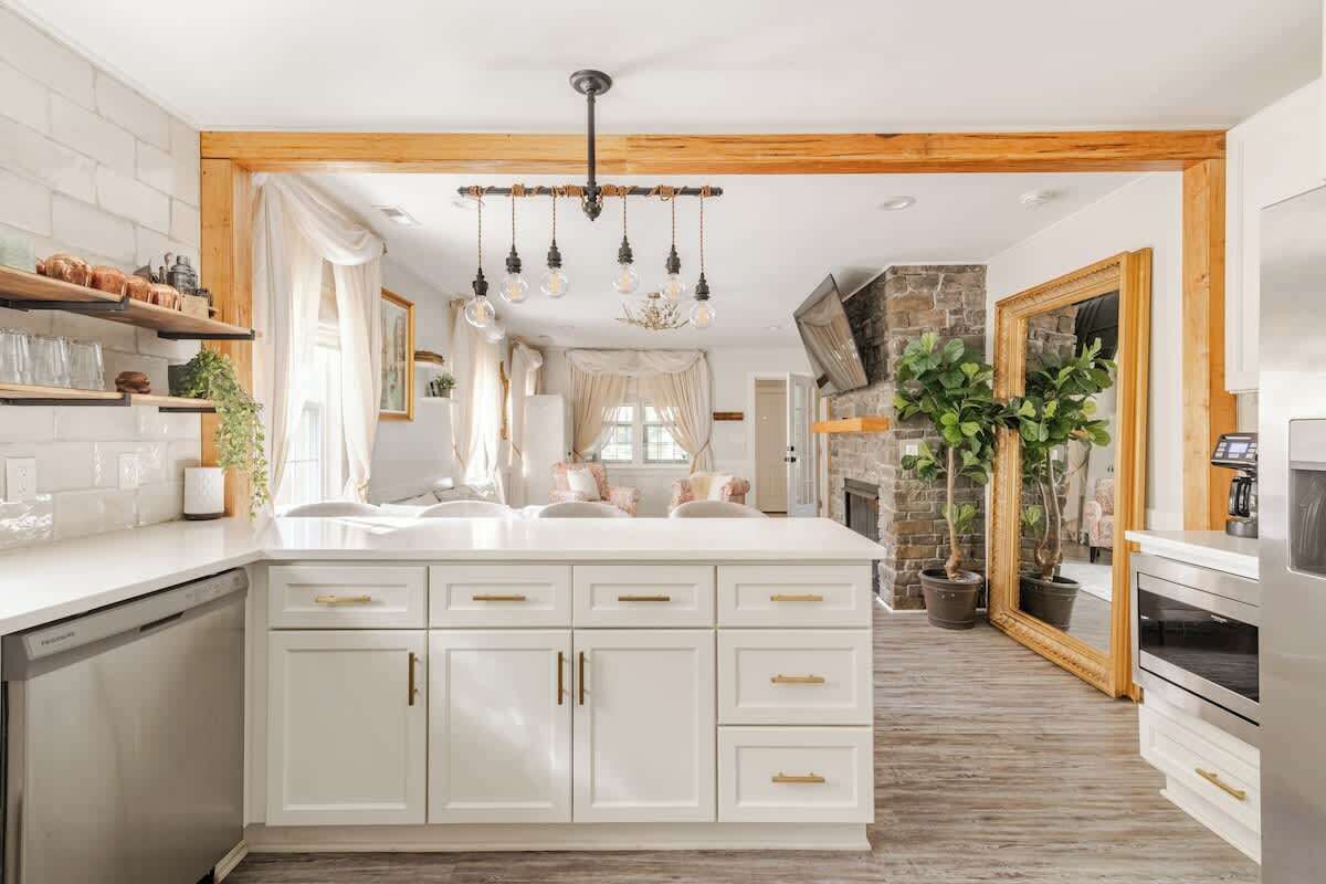 Une cuisine moderne avec des meubles blancs, un îlot central et un mur d’accent en pierre.