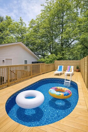 A swimming pool with wooden deck, two lounge chairs, and a wooden fence. - Hot Tub & Sauna | Near Noda Venetian Retreat (Charlotte)
