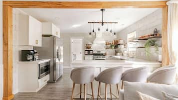 Una cocina moderna con armarios blancos, una isla central y taburetes de bar.