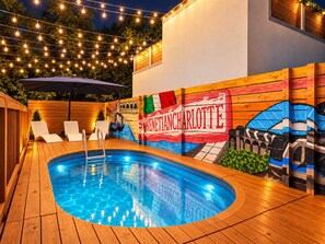 An outdoor swimming pool with a wooden deck, lounge chairs, and a mural of Venice. - Hot Tub & Sauna | Newly Renovated Outside (Charlotte)