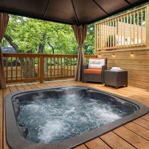 A hot tub on a wooden deck with a wicker chair and a small table.