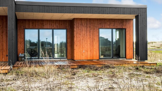 Una casa moderna con amplios ventanales y paredes exteriores de madera.