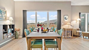 Un comedor con una mesa de madera, sillas color turquesa y vistas al campo.