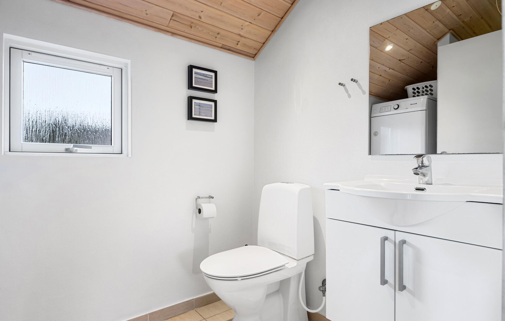 Un baño moderno con inodoro, lavabo y techo de madera.