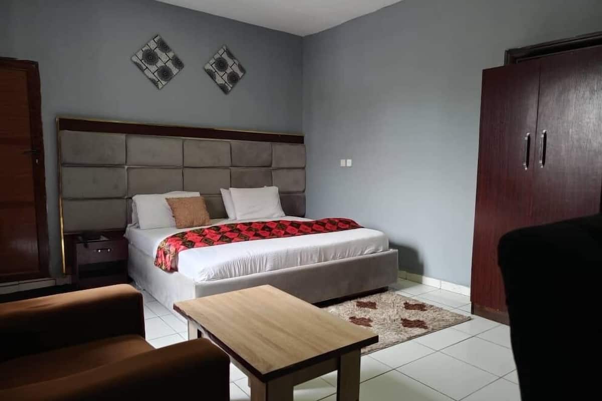 A bedroom with a bed, a wooden nightstand, a desk, and a wardrobe.