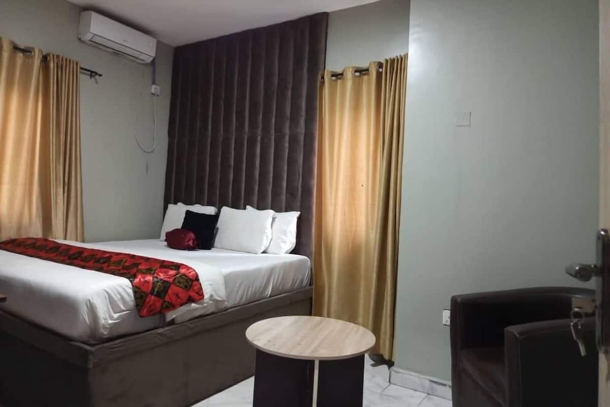 A hotel room with a bed, a round table, and a chair.