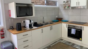 A compact kitchen with a microwave, coffee maker, sink, and oven. - Gorgeous Apartment in Kiama, minutes from Kiama's famous Blowhole & Beaches (Kiama)
