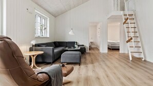 A modern living room with a sectional sofa, a small round table, a lamp, and a staircase leading to another room.