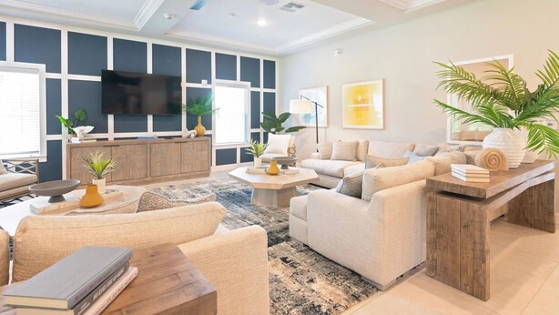 A modern living room with a large flat-screen TV, comfortable seating, a wooden coffee table, and a ceiling fan.