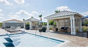 A swimming pool with lounge chairs and covered seating areas.