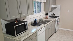 A kitchen with grey cabinets, a microwave, a stove, and a sink.