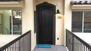 Una porta negra amb el número 201 a la paret al costat, un estri amb la paraula “hello” i un petit rellotge sobre la porta.