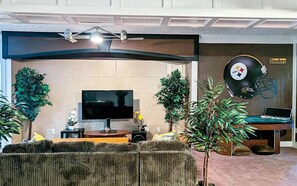A living room with a flat-screen TV, a Steelers helmet on the wall, and a sofa. - Cozy 2BR Retreat • Near Lake Lanier & Mall of GA • Private, Peaceful, Festive


 (Sugar Hill)