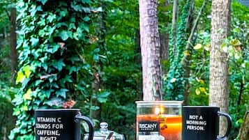 A table with three items: a black mug with text, a glass candle labeled 'Tuscany Candle', and a black mug with text.