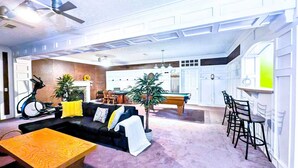 A spacious living area with a sofa, coffee table, and a dining table. There is a ceiling fan, a fireplace, and a pool table. - Cozy 2BR Retreat • Near Lake Lanier & Mall of GA • Private, Peaceful, Festive


 (Sugar Hill)