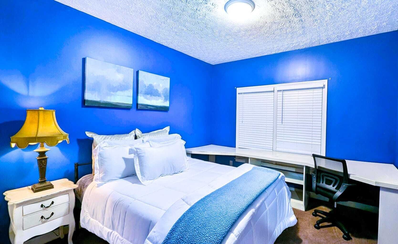 A bedroom with a bed, a desk, and a chair.