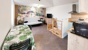 A compact living space with a sofa, a dining table, a TV, and a kitchen area. - Beautiful apartment with WiFi (Pornic)