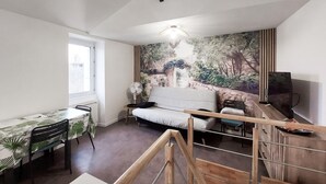 A compact living space with a dining area, a sofa, a TV, and a mural. - Beautiful apartment with WiFi (Pornic)
