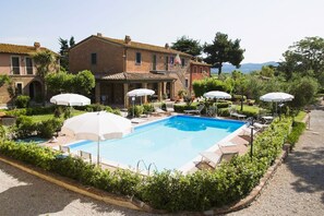 A swimming pool surrounded by lounge chairs and umbrellas, with a building in the background. - 50 sqm apartment located on the first floor consisting of a living room with double sofa bed and satellite TV, equipped kitchenette, refrigerator.A double bedroom, a bedroom with two single beds and bathroom. Private parking. (Donoratico)