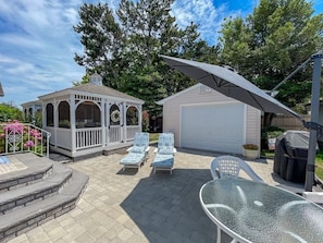 Um gazebo, área de estar externa, garagem e espaço para churrasco.