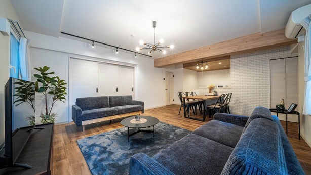 Ein modernes Wohnzimmer mit grauem Sofa, Couchtisch und Essbereich mit Holztisch und Stühlen.