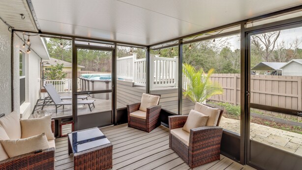Une terrasse couverte, meublée de mobilier en osier, une piscine et une vue sur le jardin arrière.