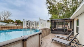 Un jardin avec une piscine, des chaises longues et un espace salon abrité.