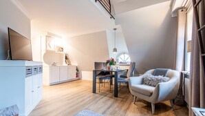 Um apartamento loft moderno com área de refeições, sofá e televisão.