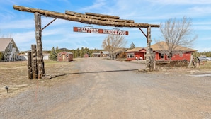 A rustic wooden archway with a sign reading "TRAPPERS RENDZVOUS" over a gravel road leading to a red building. - Charming 2-bedroom B&B with WiFi, AC in gorgeous Williams (Williams)