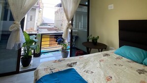 Una camera da letto con un letto, tende, un tavolino e una pianta in vaso.