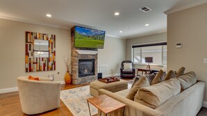 Una sala de estar con chimenea de piedra, un televisor de pantalla plana grande, un sofá cómodo y un espejo decorativo.