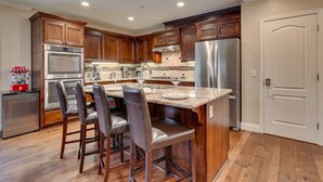 Una cocina moderna con armarios de madera, electrodomésticos de acero inoxidable y una isla central con taburetes de bar.