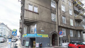 Un bâtiment avec une devanture de magasin, un panneau indiquant qu’il est interdit de se garer, et une voiture rouge stationnée dans la rue.