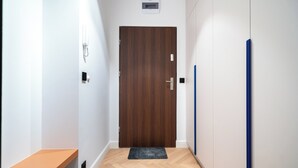 Un couloir avec une porte en bois, un banc et un élément vertical bleu sur le mur.