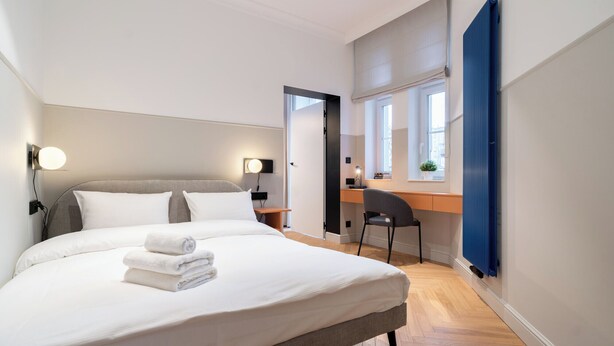 Une chambre d’hôtel moderne, dotée d’un grand lit, d’un bureau et d’une chaise.