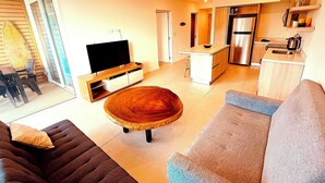 Uma sala de estar moderna com uma TV de tela plana, uma mesa de centro de madeira e um sofá.