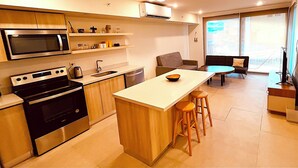 Uma cozinha moderna com uma ilha central, banquetas, um espaço de refeições com mesa e cadeiras, e uma janela ampla com vista.