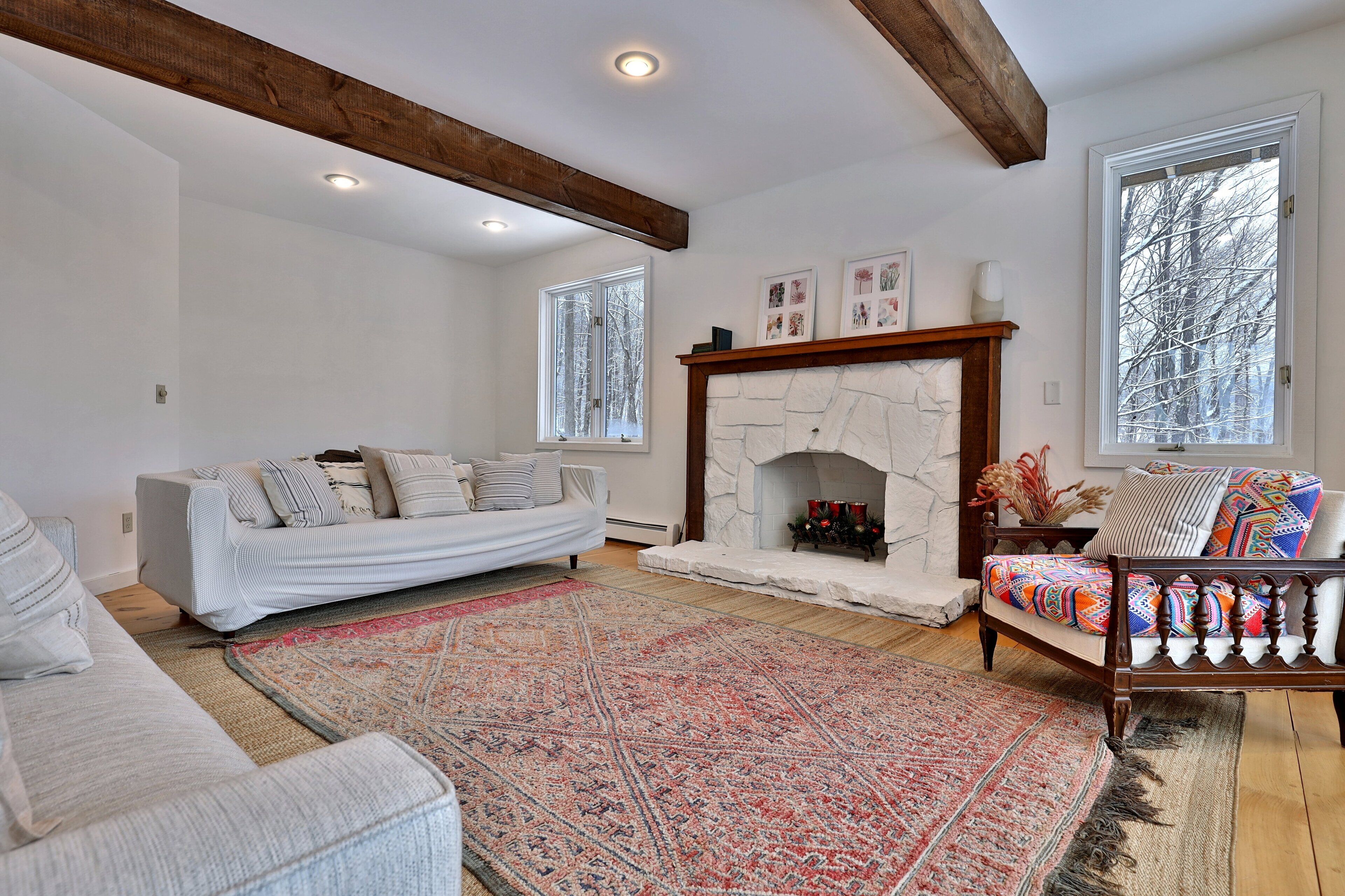 A living room with a stone fireplace, a sofa, a chair, and a large rug.